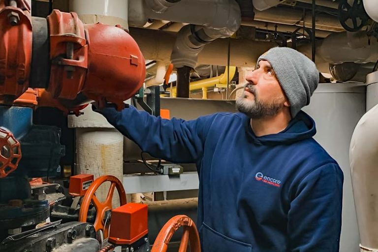 Encore Fire Protection technician examining a fire sprinkler system in a building, ensuring operational safety
