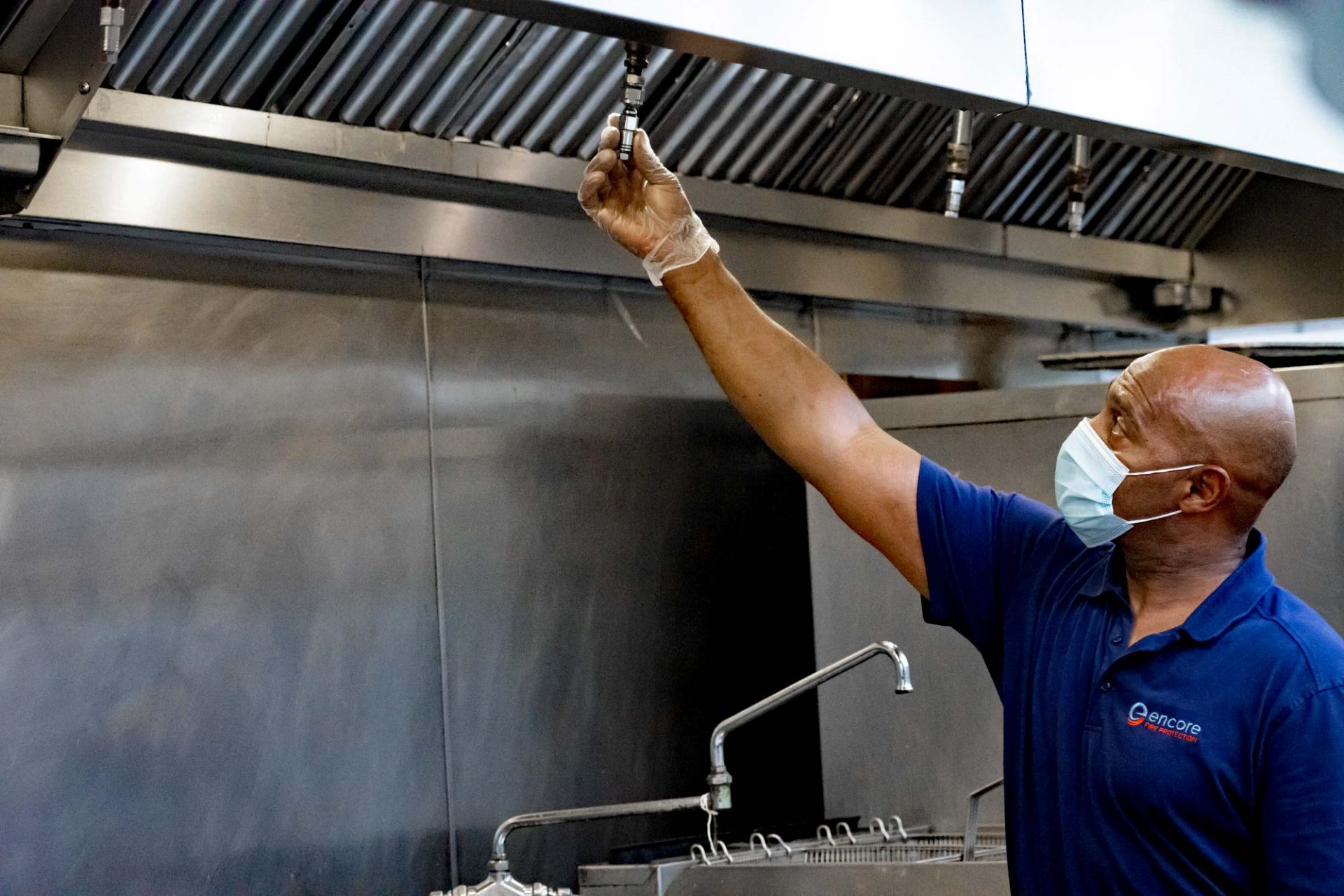 Encore technician inspecting a kitchen fire suppression system in commercial kitchen